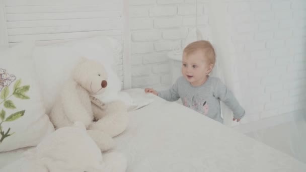 Meisje touch de beer in de buurt van het bed. Slow-Motion. De mijlpaal van de baby, peuter, 1 jaar oud. Gelukkige jeugd — Stockvideo