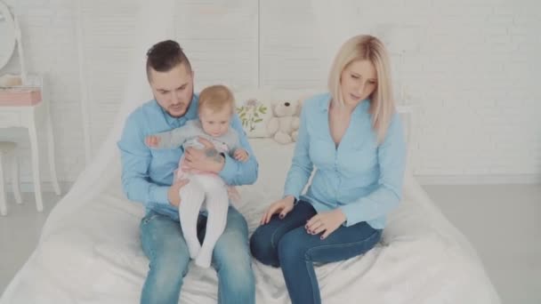 La coppia sta giocando con il loro bambino. Sedile di famiglia sul letto con la loro bellissima figlia. Pietra miliare del bambino, bambino, 1 anno. Buona infanzia. — Video Stock