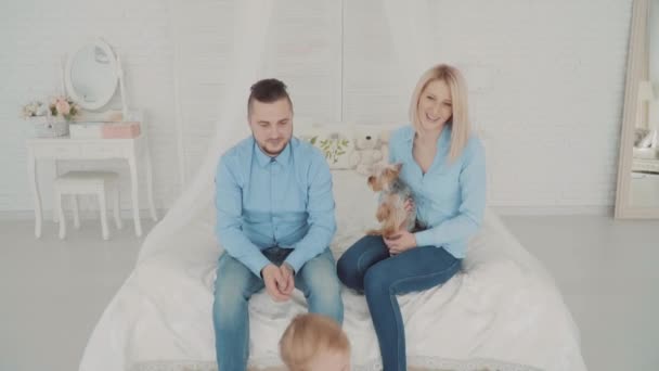 La pareja está jugando con su bebé. Asiento familiar en la cama con su hermosa hija pequeña. Hito del bebé, niño, 1 año de edad. Feliz infancia. — Vídeos de Stock