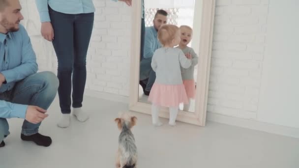 美丽的小女孩和她的家人和狗呆在镜子旁。慢动作。婴儿里程碑, 蹒跚学步, 1 岁。快乐童年 — 图库视频影像