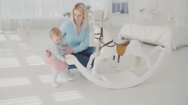 Moeder en dochter spelen in de buurt van swing. Slow-motion. Gelukkig blonde vrouw en baby zitten in de buurt van schommel — Stockvideo