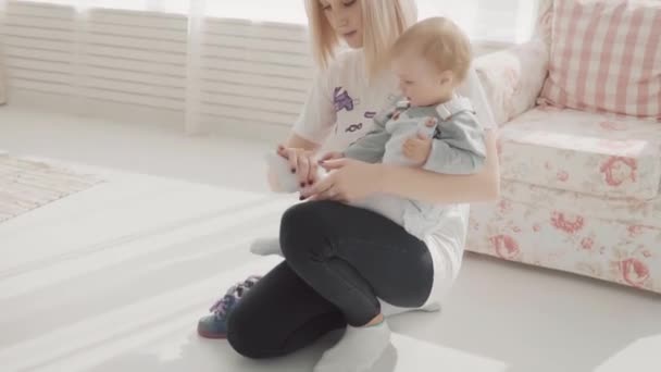 La joven madre se puso zapatos para su adorable bebé. Familia feliz. Movimiento lento — Vídeos de Stock