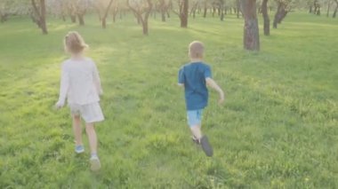 Aktif erkek ve kız parkta ağaçların yakınındaki çalıştırın. Güzel doğa. Ağır çekim