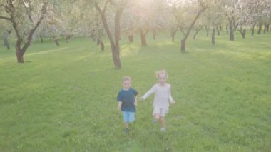 Aktif erkek ve kız parkta ağaçların yakınındaki çalıştırın. Güzel doğa. Ağır çekim