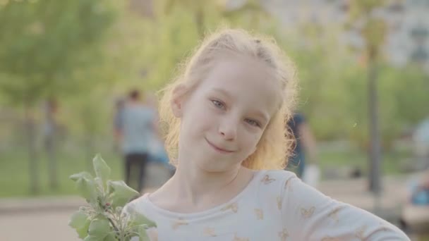 Portreto de hermosa chica sonriente en el parque. Sol y naturaleza agradable. Movimiento lento — Vídeos de Stock