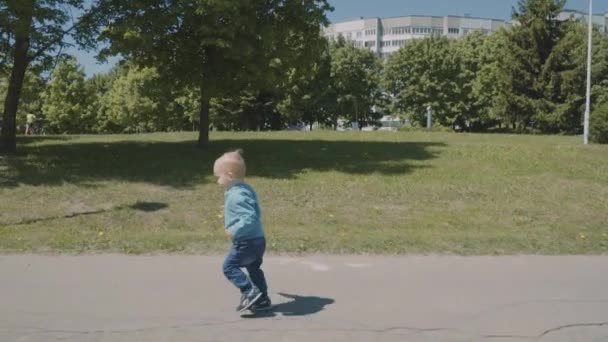 Lite härlig pojke kör i parken. Slow motion — Stockvideo