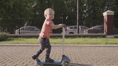 parkta tekme scooter üzerinde küçük tatlı çocuk. Ağır çekim