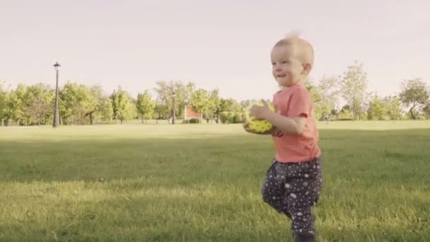 Pequeño niño hermoso jugando con la pelota en el parque. Movimiento lento — Vídeos de Stock