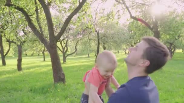 Молодой отец играет со своим сыном, бросает его, кружит вокруг — стоковое видео