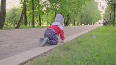 Çok güzel yürümeye başlayan çocuk, çiçek açan ağaçlar ile sunset Bulvarında bir yolda oynayan çocuk