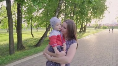 Genç Anne sarılma ve öpüşme oğlu, hafta sonu birlikte, tembel sabah, sıcak ve rahat sahne rahatlatıcı ve parkta oynarken küçük oğlu ile. yavaş mo