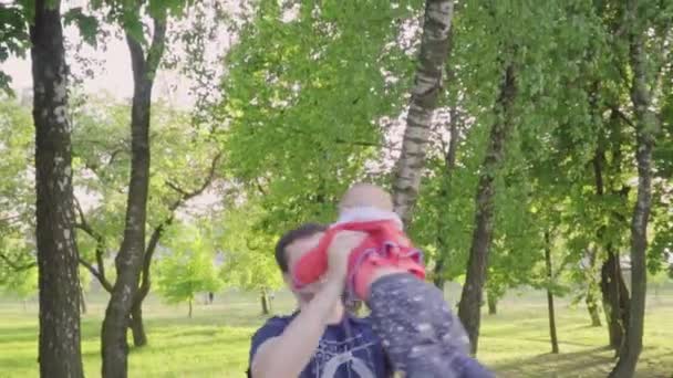 Junger Vater spielt mit seinem Sohn, wirft ihn auf, kreist — Stockvideo