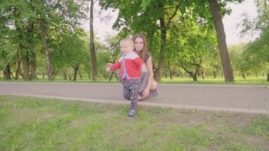 Mutlu küçük çocuk güneş ışığı altında çimlerin üzerine ailesi Park ile oynuyor