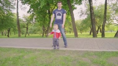 Mutlu küçük çocuk güneş ışığı altında çimlerin üzerine ailesi Park ile oynuyor