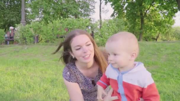 Gelukkige Kaukasische mensen en kinderen. Witte motheris spelen met zoon in het park. Moeder lacht en lacht met mannelijke kind. Leuk voor vrouw schattige babyjongen in park. Slow motion — Stockvideo