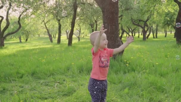 Kleine jongen kijkt zeepbellen in park door ouders hand. slow-mo — Stockvideo
