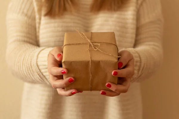 close-up of a woman\'s hands with red nails and with a gift. Christmas gift