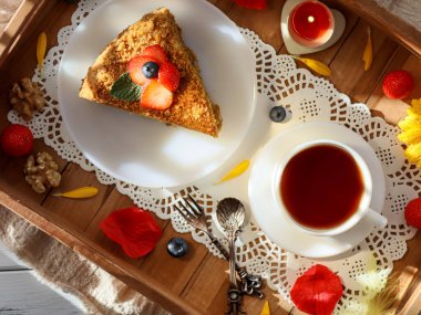 Bir fincan çay tabağında ballı kek, ahşap tabakta, yakın plan..