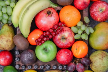 farklı meyveler ve meyveler ahşap bir tepside taştan bir arka planda, yakın plan üst manzara.