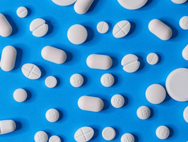 Mavi bir kağıda serpiştirilmiş bir sürü farklı hap var..