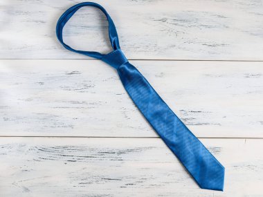 Bir adamın mavi kravatı beyaz ahşap bir masanın üzerinde çaprazlama duruyor..