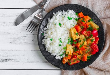 Sebzeli pilav ve baharatlı soslu tavuk eti ahşap bir masada, yakın plan üst manzara..
