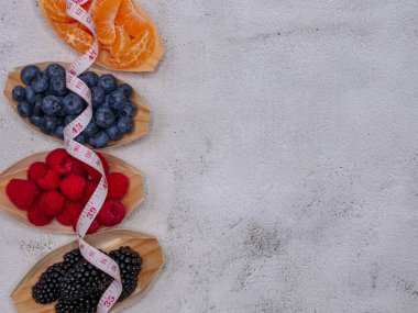 Yaban mersini ve mandalina dilimleri tahta teknelerde solda bir kurdele, sağda yazı için bir yer, üstte yakın çekim..