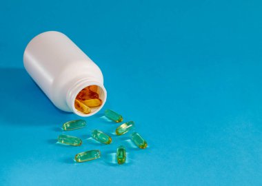 haplar ve şişe soldaki mavi arka planda beyaz bir şişe ve sağdaki yazı için dağınık sarı haplar var..