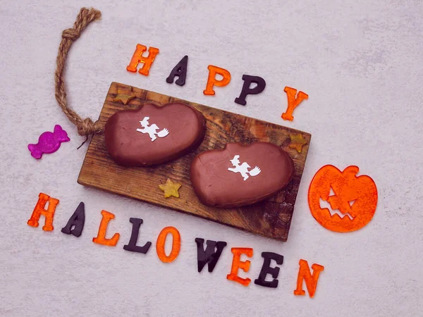 Cadılar Bayramı balkabağı şeklindeki kurabiyeler ahşap bir tabakta duruyor ve üzerinde 