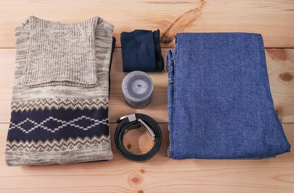 Kemerli, çoraplı ve süveterli erkek kot pantolonu ortadaki ahşap bir rafta, yakın plan üst manzara.