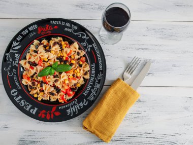 Beyaz ahşap bir masada, tabakta hazır farfalle makarnası. Sağda yazı için yer var. Üst manzara..