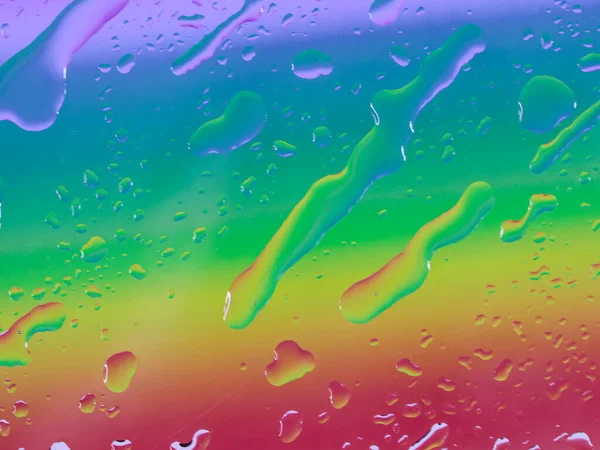 Beautiful colored background of gentle blue and pink color with large drops of water on it, top view close-up.