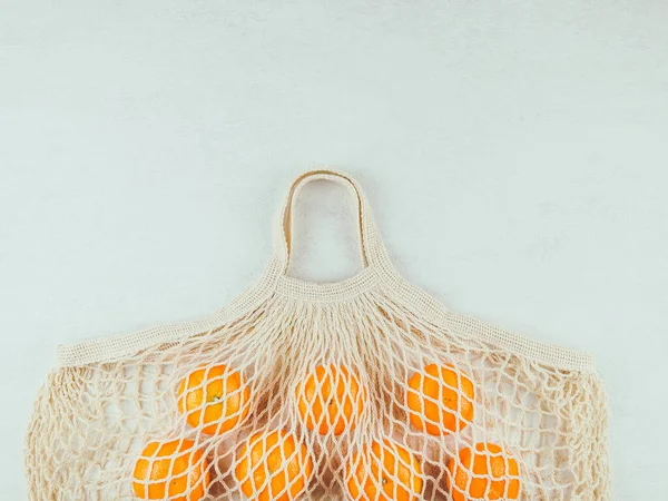 oranges in a bagOranges in a cotton bag on the left on a white background with space for text on the right, top view close-up.