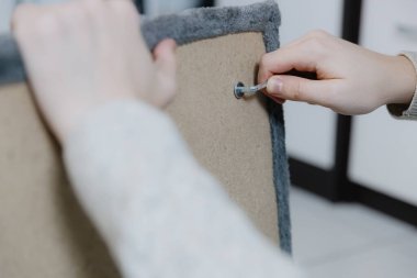 Tanınmayan genç beyaz bir adam, küçük bir tornavida kullanarak vida vidalıyor, yeni bir kedi evi yapıyor, oturma odasında oturuyor, yan görüntüsü çok yakın. Kedi mobilyalarının ve tırmalama direklerinin birleşimi.