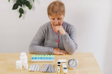 Gri kazaklı son sınıf güzel bir kadının portresi ahşap masada özenle oturuyor ve gündüzleri odada haplara, organizatörlere, termometrelere ve alarma bakıyor. Teknoloji kullanma zamanı kavramı