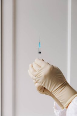 Kafkasyalı tanınmayan doktorların dikey portresi steril eldivenlerle ellerinde tek kullanımlık şırıngayla ev kliniği koğuşunda yakın plan çekimleri yapıyorlar. Abdominal hastalıklar, hemşire hizmetleri.