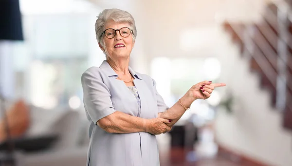 Smuk Senior Kvinde Peger Siden Smilende Overrasket Præsentere Noget Naturligt - Stock-foto