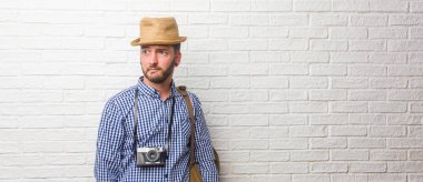 Sırt çantası ve bir vintage fotoğraf makinesi şüphe ve karışık, düşünme, bir fikir ya da bir şey hakkında endişeli giyen genç yolcusu adam. Bir harita tutarak.