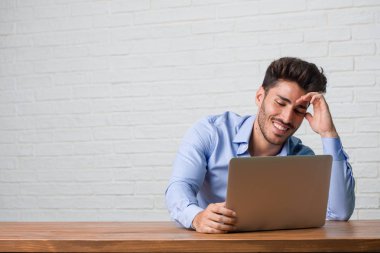 Rahat ve neşeli, gülen ve having fun, bir dizüstü bilgisayarda çalışma ve oturma genç iş adamı kendinden emin ve başarılı hissediyor
