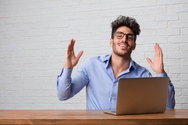 Silah, bir zafer ya da başarı, piyango kazanan kutluyor yükselterek oturma ve çalışma üstünde a laptop çok mutlu ve heyecanlı, Genç iş adamı