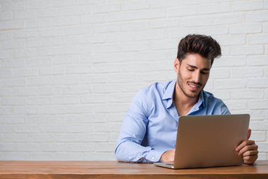 Rahat ve neşeli, gülen ve having fun, bir dizüstü bilgisayarda çalışma ve oturma genç iş adamı kendinden emin ve başarılı hissediyor