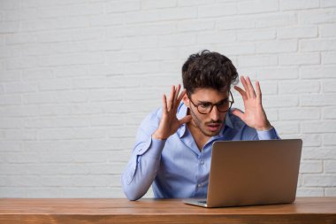 Oturma ve bir dizüstü bilgisayar üzerinde çalışan genç iş adamı şaşırttı ve şok, kazanmak kavramı geniş gözlü, heyecanlı bir teklif veya yeni bir iş arıyorum