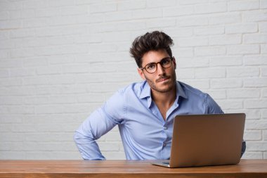 Oturma ve çalışma üstünde a laptop çok kızgın ve üzgün, çok gergin, öfkeli, negatif ve çılgın çığlık genç iş adamı