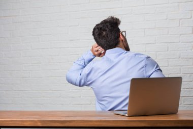 Oturma ve geri gösterilen, poz ve bekleyen, geriye dönüp baktığımda bir dizüstü bilgisayarda çalışan genç iş adamı