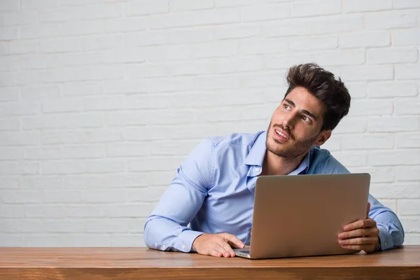 Joven Hombre Negocios Sentado Trabajando Portátil Mirando Hacia Arriba Pensando —  Fotos de Stock