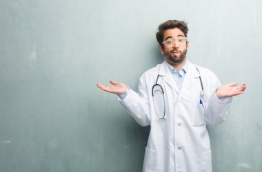 Genç dostu Doktor adam ile şüphe ve omuzlar, shrugging bir kopya alanı kavramı kararsızlık ve güvensizlik, hakkında bir şey belirsiz bir grunge duvara