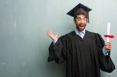 Genç ağzı açık, atlama ve gururlu adam mutlu, sürpriz bir teklif ya da bir promosyon tarafından bir grunge duvara bir kopya alanı çığlık ile mezun oldu.