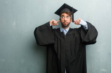 Genç adam bir grunge duvara eller, kızgın ve bazı ses işitme yorgun kulaklarıyla kapsayan bir kopya alanı mezun oldu