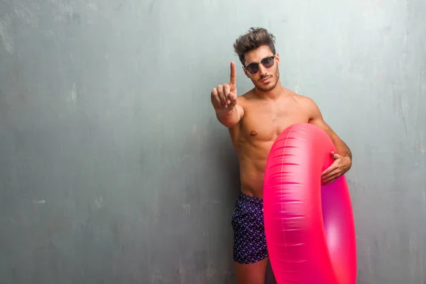 Young Athletic Man Wearing Swimsuit Grunge Wall Showing Number One — Stock Photo, Image