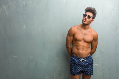 Bir grunge duvar şüphe ve karışık, düşünme, bir fikir ya da bir şey hakkında endişeli karşı bir mayo giyen genç atletik erkek